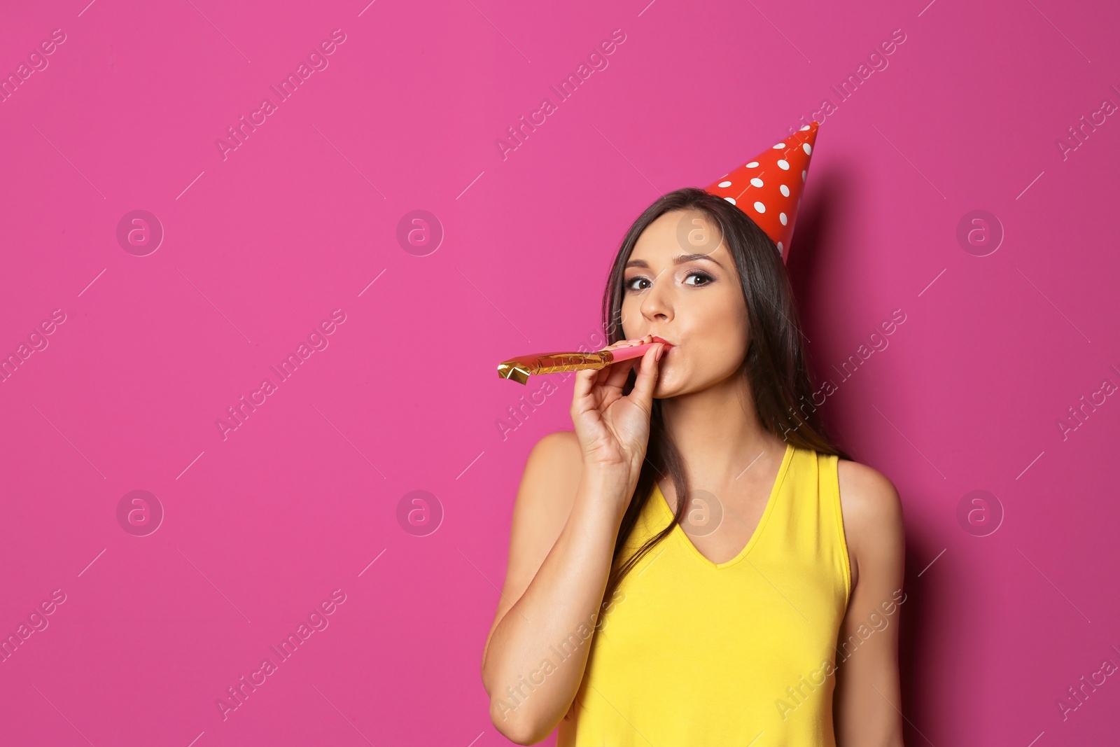 Photo of Young woman with party blower on color background. Birthday celebration