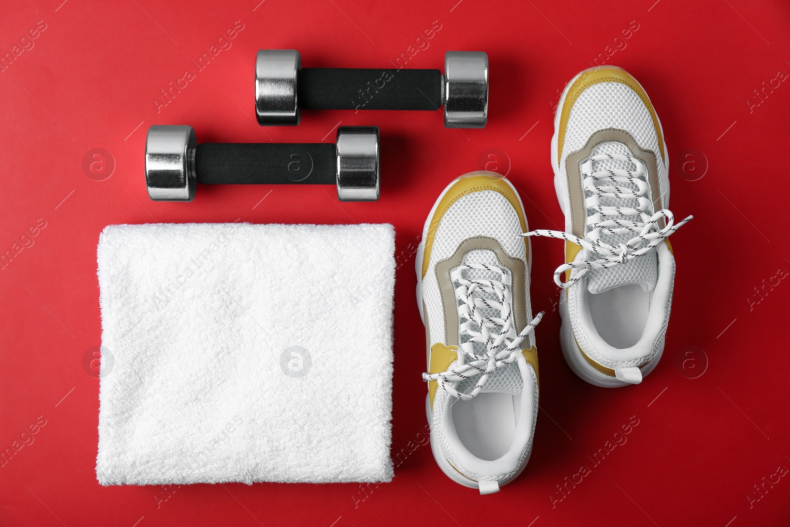 Photo of Flat lay composition of training shoes, towel and dumbbells on color background