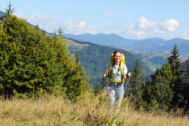 Photo of Woman with trekking poles hiking in mountains