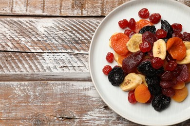 Photo of Mix of delicious dried fruits on wooden table, top view. Space for text