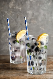 Glasses of drink with blueberry ice cubes on table