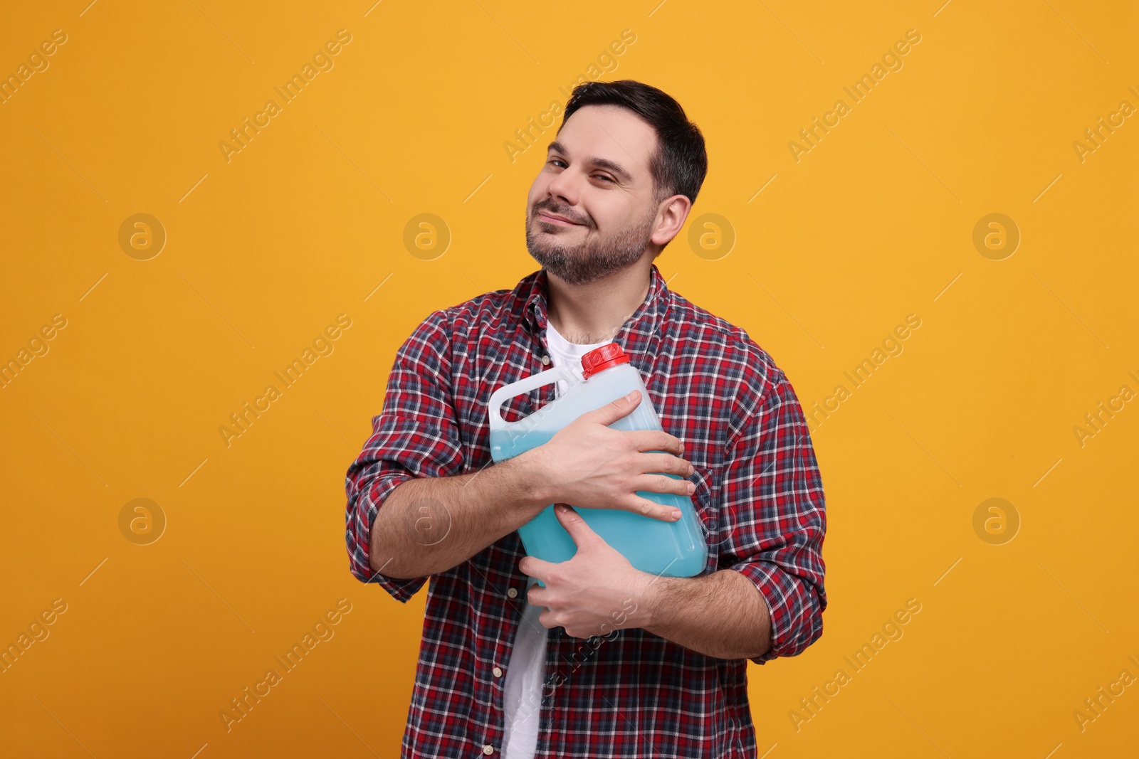 Photo of Man holding canister with blue liquid on orange background