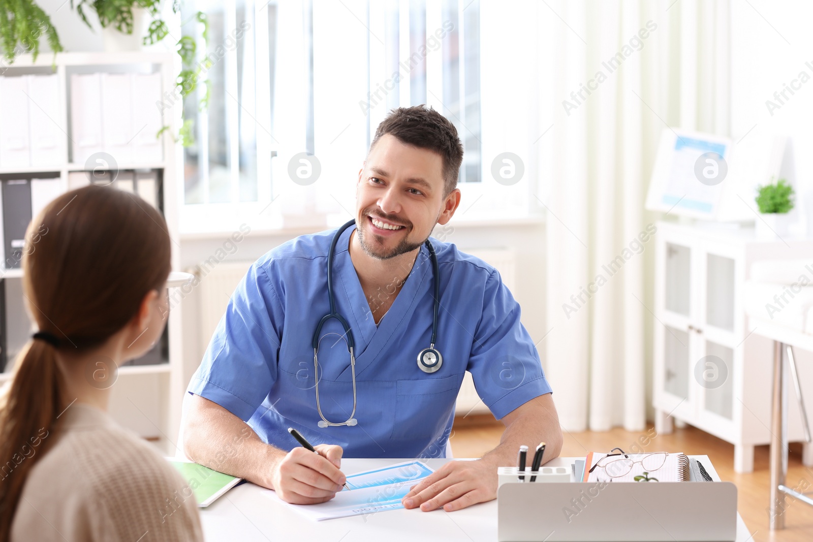 Photo of Doctor consulting patient at desk in clinic