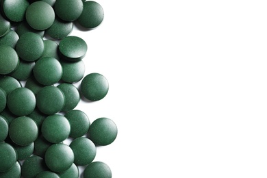 Photo of Green spirulina pills on white background, top view