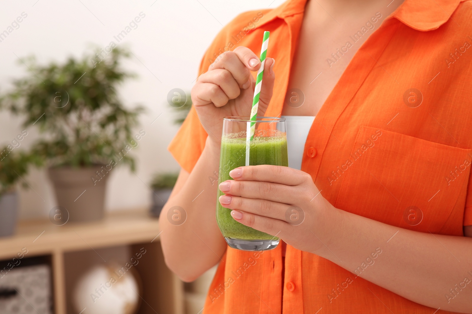 Photo of Woman holding glass with delicious smoothie indoors, closeup