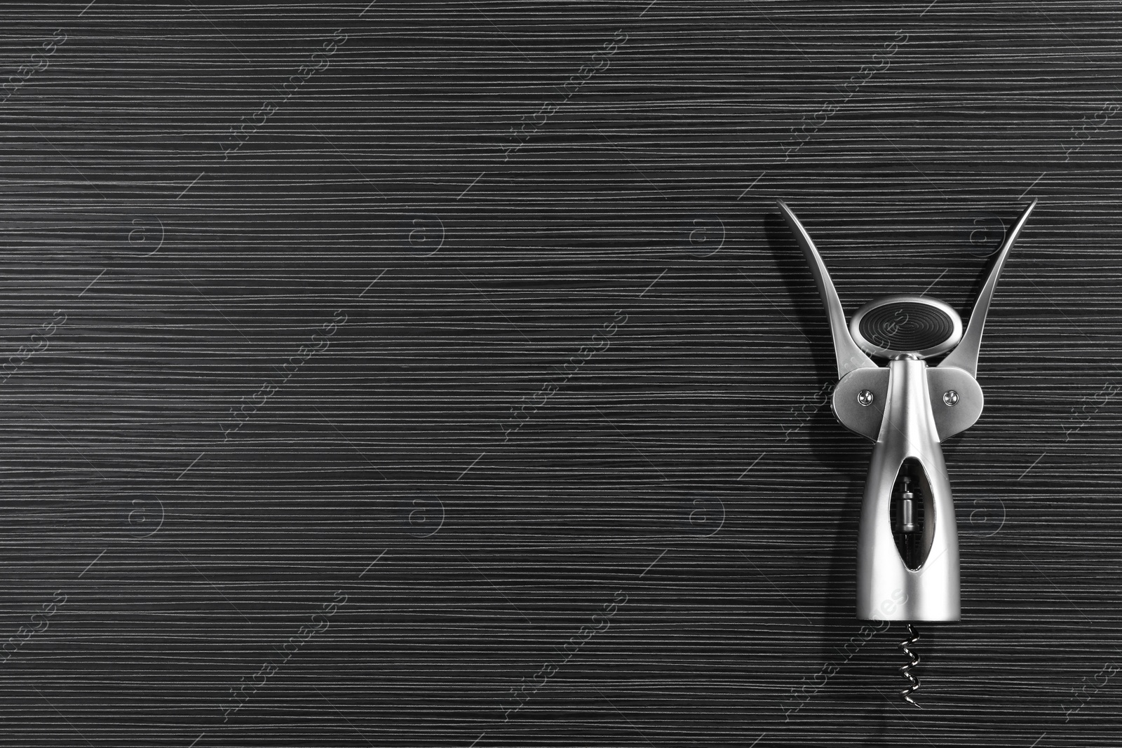 Photo of One wing corkscrew on black wooden table, top view. Space for text