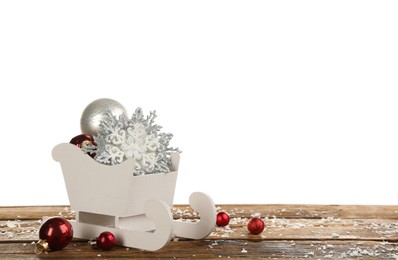 Photo of Decorative sleigh with Christmas ornaments on wooden table. Space for text