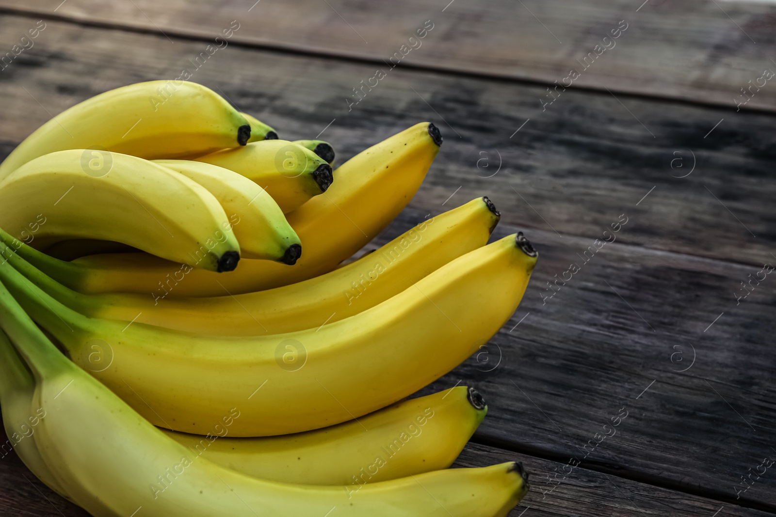 Photo of Ripe yellow bananas on wooden table, closeup. Space for text