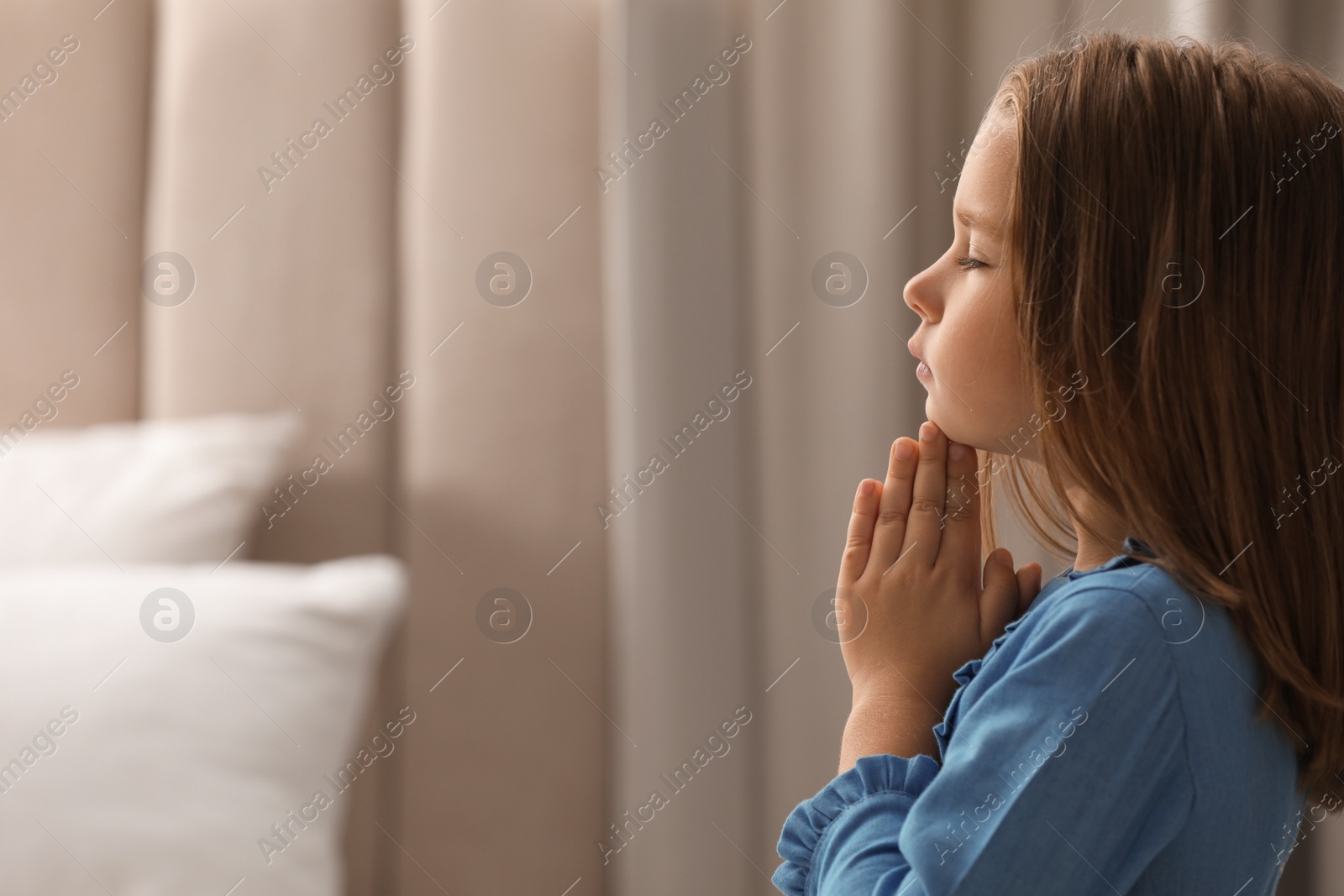 Photo of Cute little girl saying bedtime prayer at home. Space for text