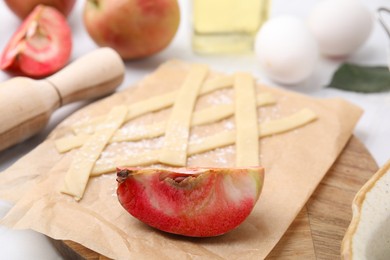 Photo of Making apple pie. Fruit and sliced dough on white table, closeup