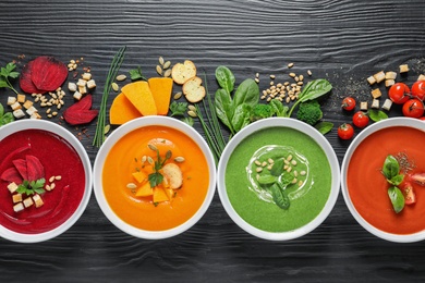 Flat lay composition with various soups and ingredients on wooden background. Healthy food