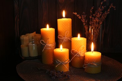 Photo of Beautiful burning beeswax candles and dried lavender flowers on table