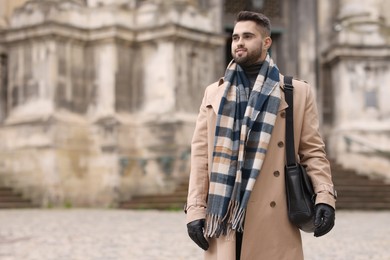 Photo of Smiling man in warm scarf outdoors. Space for text