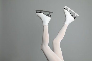 Photo of Woman in elegant white ice skates on grey background, closeup of legs. Space for text