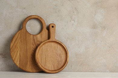 Wooden cutting boards on white table near textured wall, space for text