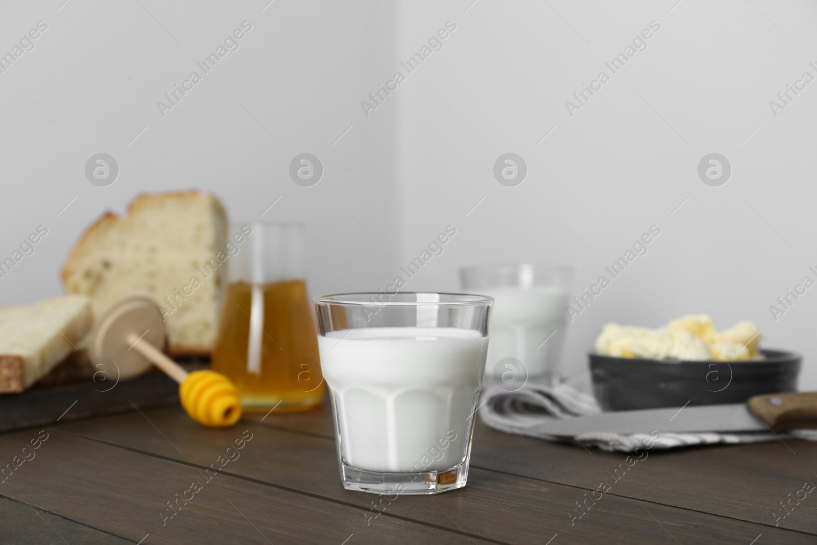 Photo of Delicious milk, honey, butter and bread served for breakfast on wooden table