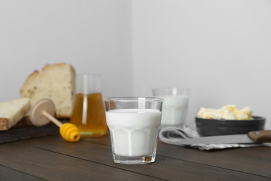 Photo of Delicious milk, honey, butter and bread served for breakfast on wooden table