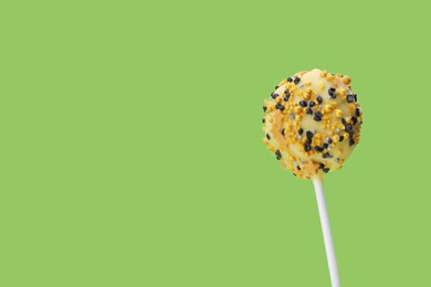 Photo of Delicious confectionery. Sweet cake pop decorated with sprinkles on light green background, closeup. Space for text