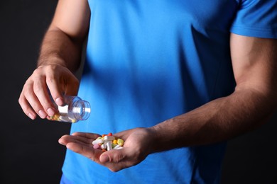 Man with bottle of pills on black background, closeup. Doping concept