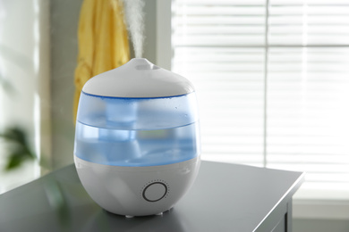 Photo of Modern air humidifier on table at home