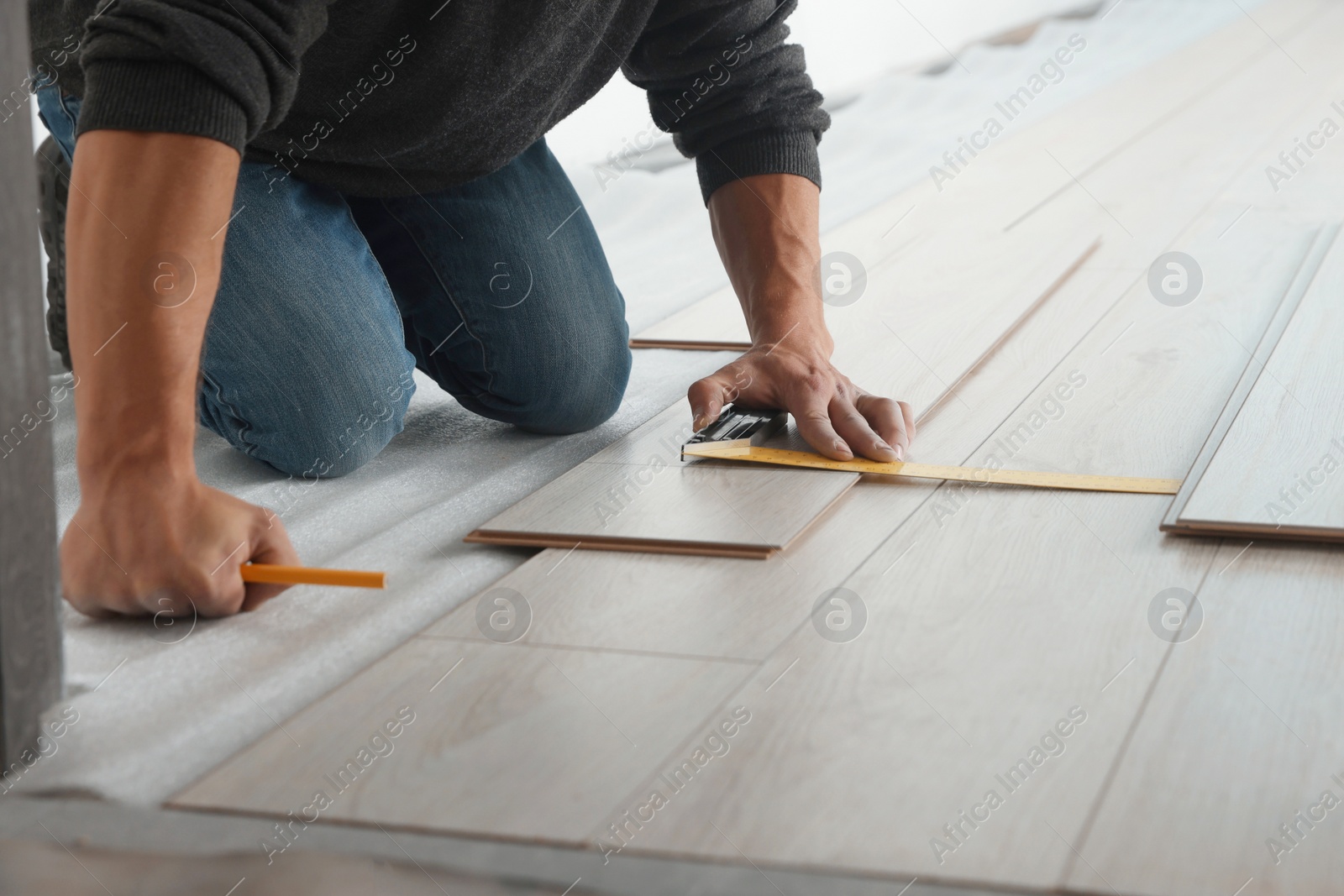 Photo of Worker installing new laminate flooring in room, closeup