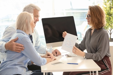 Photo of Female manager consulting mature couple in office