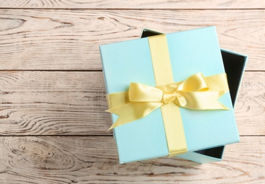 Elegant gift box with bow on wooden background, top view