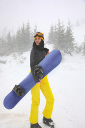 Photo of Young woman with snowboard wearing winter sport clothes outdoors