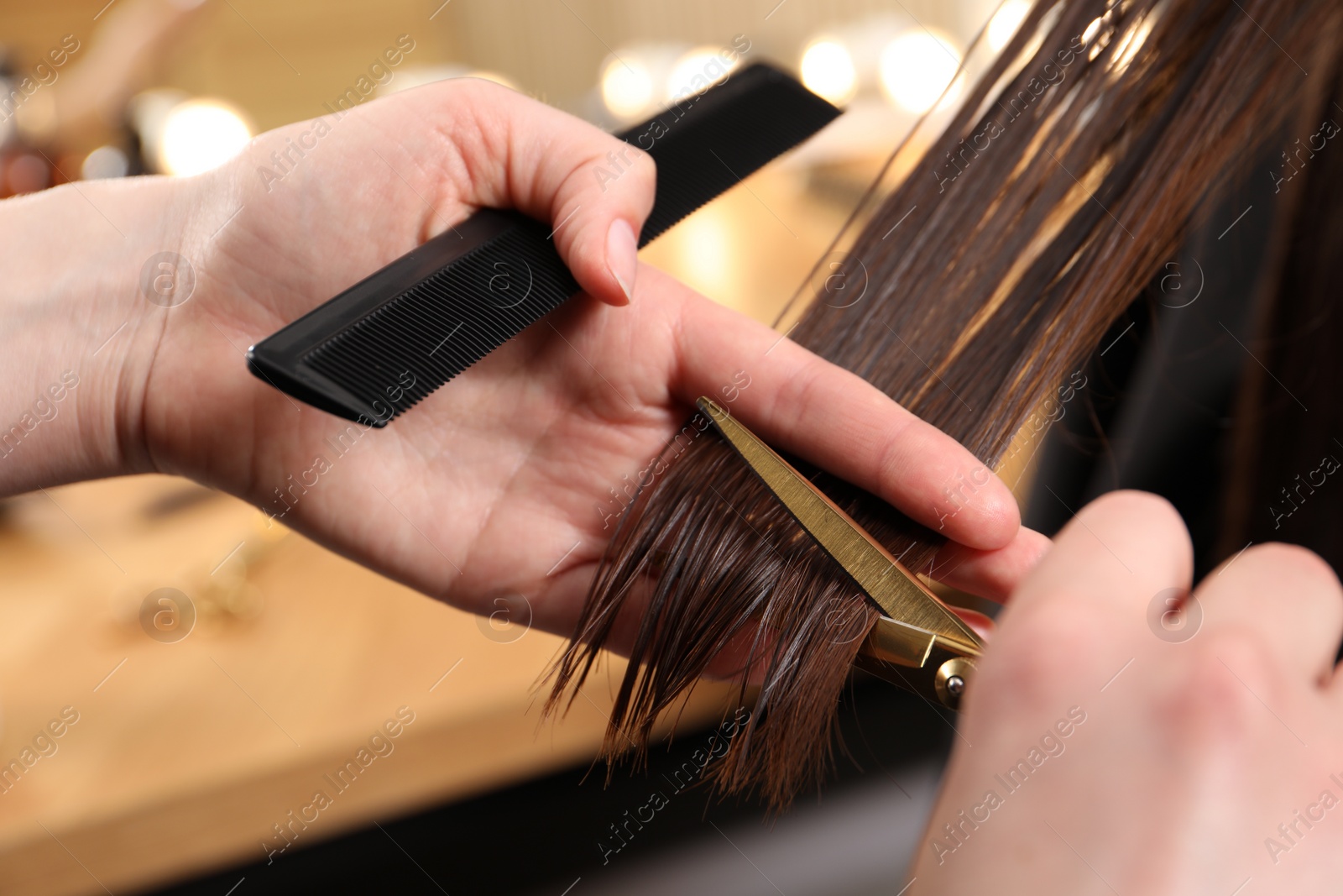 Photo of Hairdresser cutting client's hair with scissors in salon, closeup