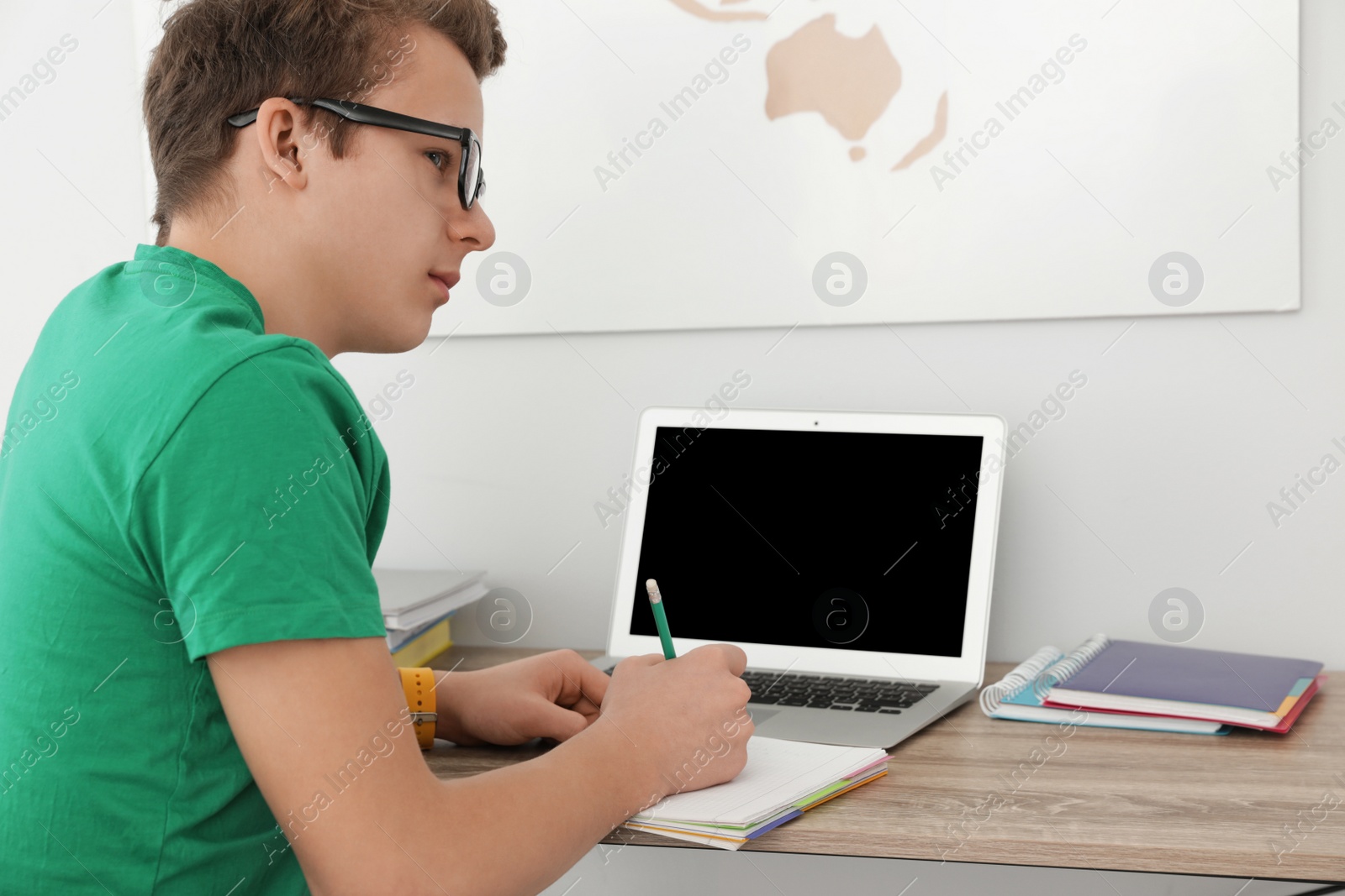 Photo of Teenager boy doing his homework at desk indoors