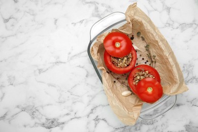 Uncooked stuffed tomatoes with minced beef, bulgur and mushrooms in baking dish on white marble table, top view. Space for text