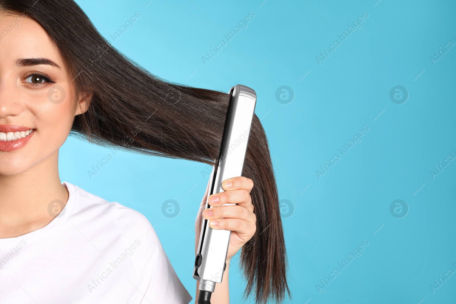 Photo of Happy woman using hair iron on color background. Space for text