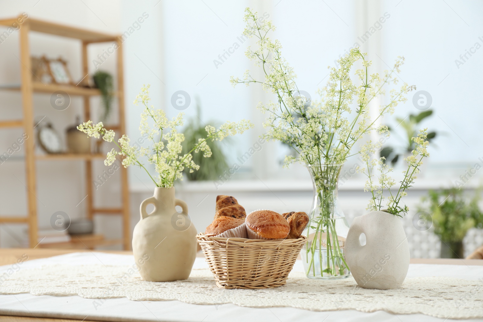 Photo of Fresh pastries and beautiful flowers on table in stylish dining room