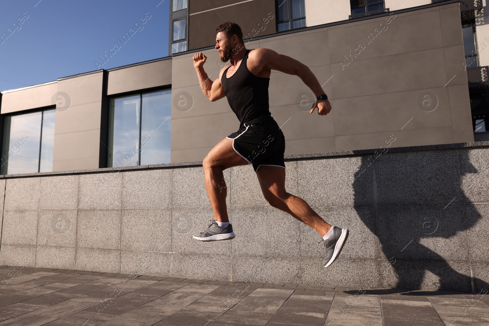 Photo of Young man running near building outdoors. Space for text