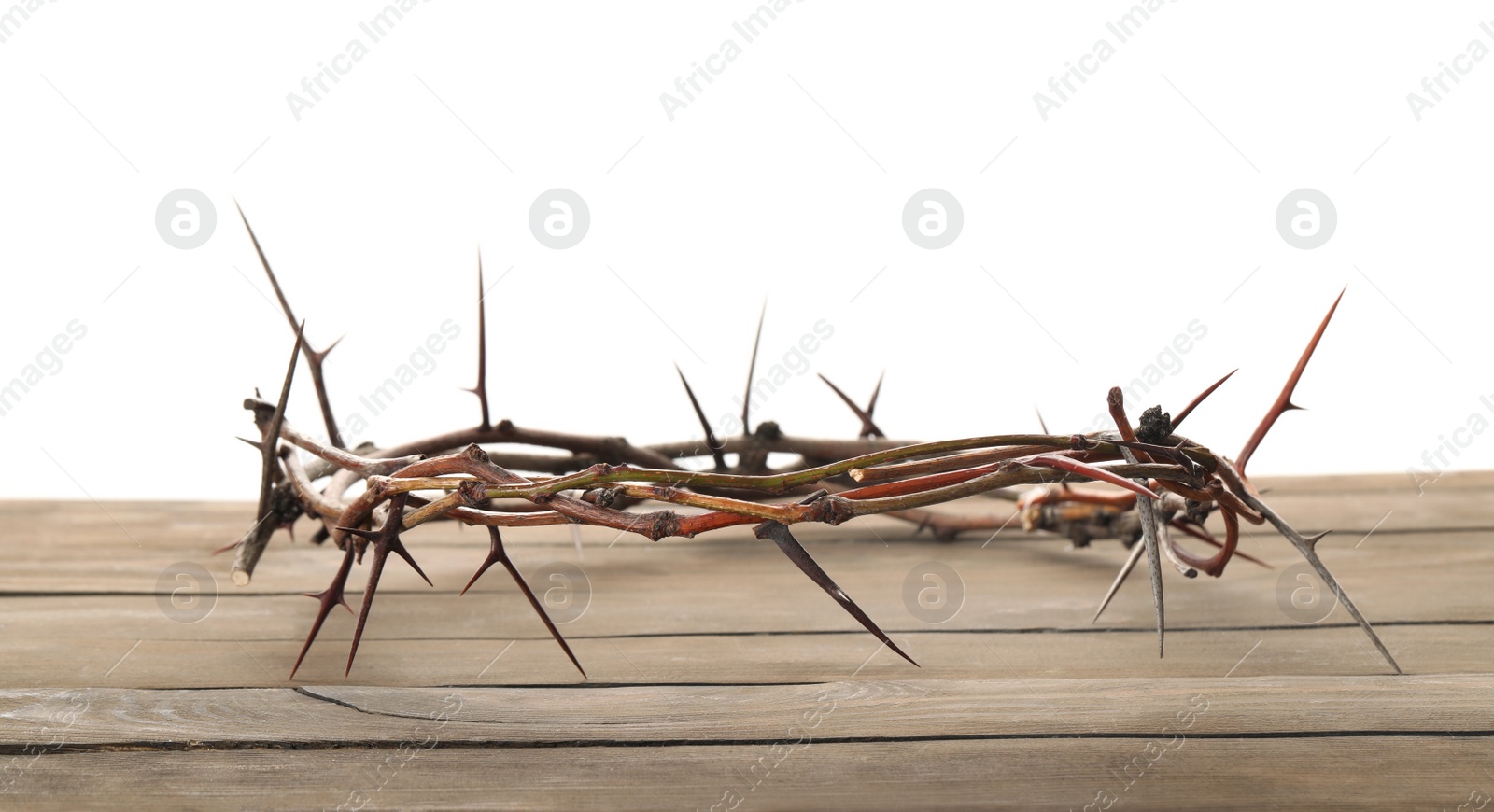 Photo of Crown of thorns on wooden table against white background, space for text. Easter attribute