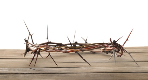 Photo of Crown of thorns on wooden table against white background, space for text. Easter attribute