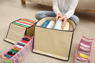 Photo of Woman folding clothes on floor at home, closeup. Japanese storage system