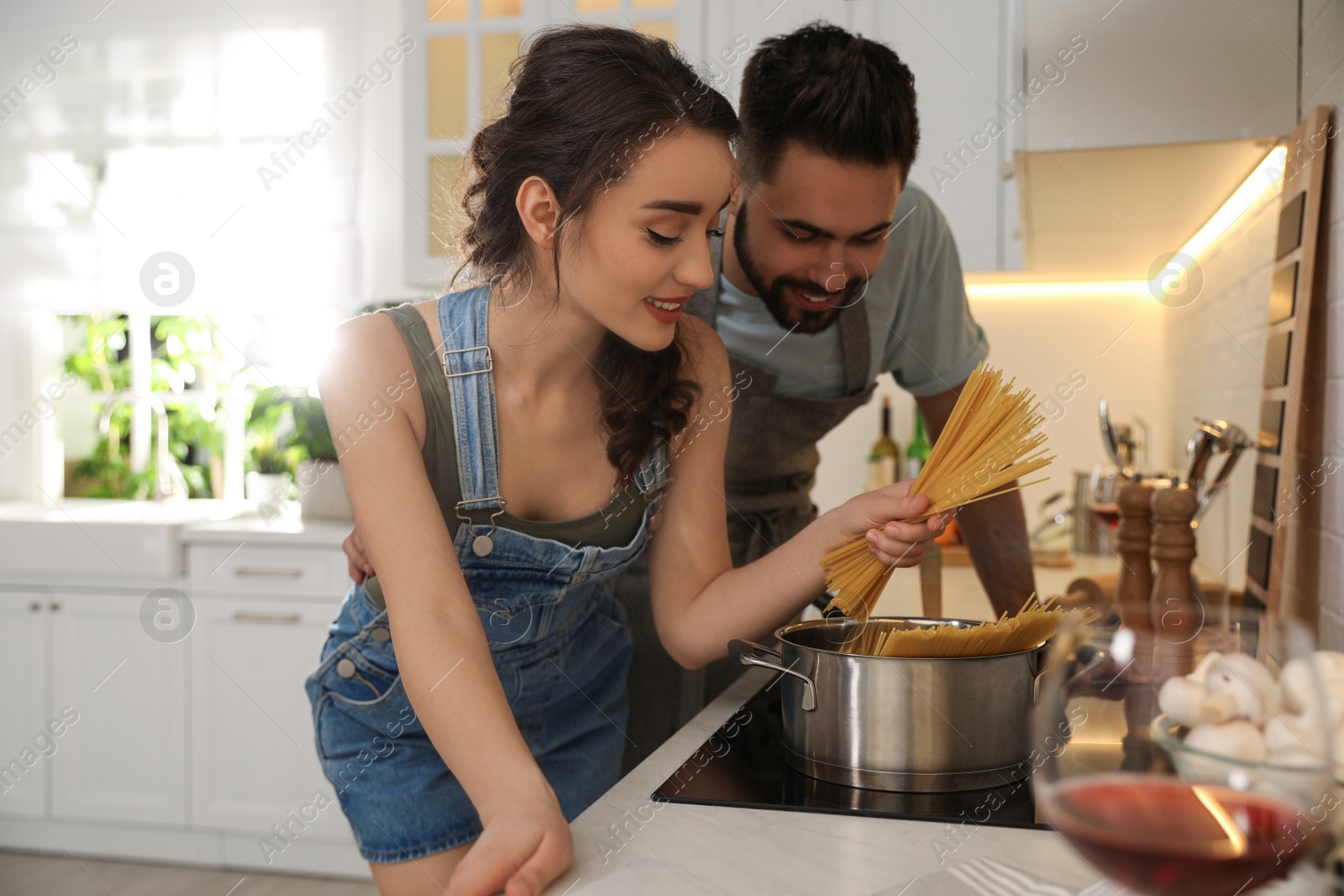 Photo of Lovely young couple cooking pasta together in kitchen