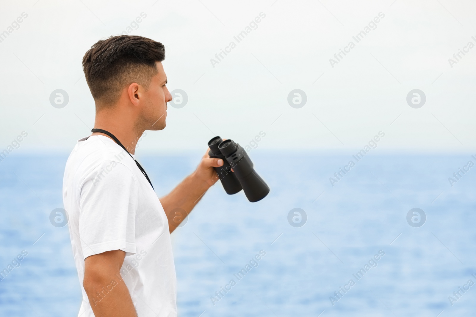 Photo of Handsome male lifeguard with binocular near sea