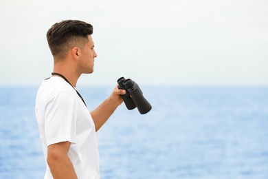 Handsome male lifeguard with binocular near sea