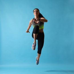 Photo of Athletic young woman running on light blue background