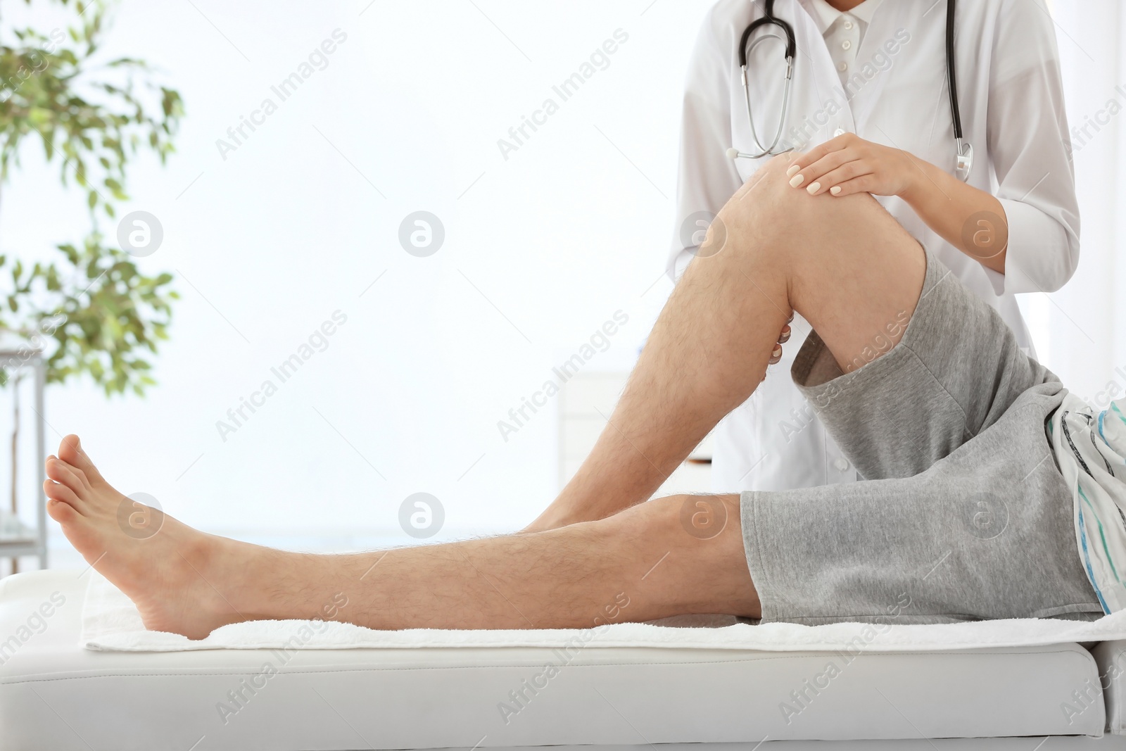 Photo of Doctor examining male patient with injured leg, closeup