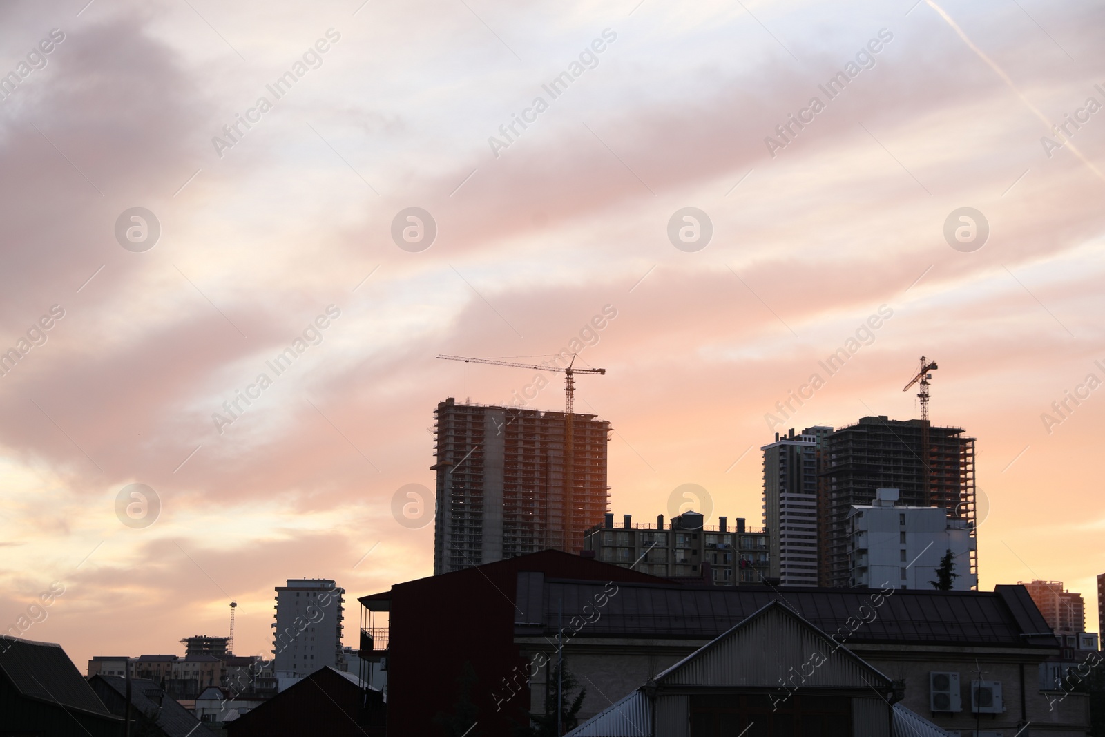 Photo of Tower cranes near unfinished buildings in city