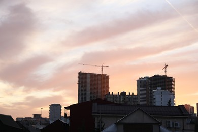 Photo of Tower cranes near unfinished buildings in city