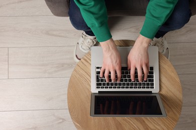 Man working with laptop at wooden table, top view. Space for text