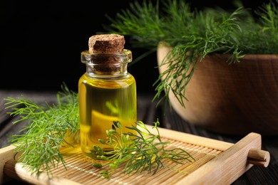 Photo of Bottle of essential oil and fresh dill on table, closeup