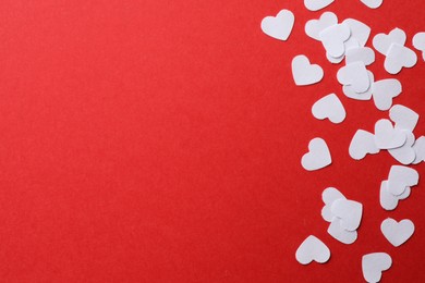 Photo of White paper hearts on red background, flat lay. Space for text