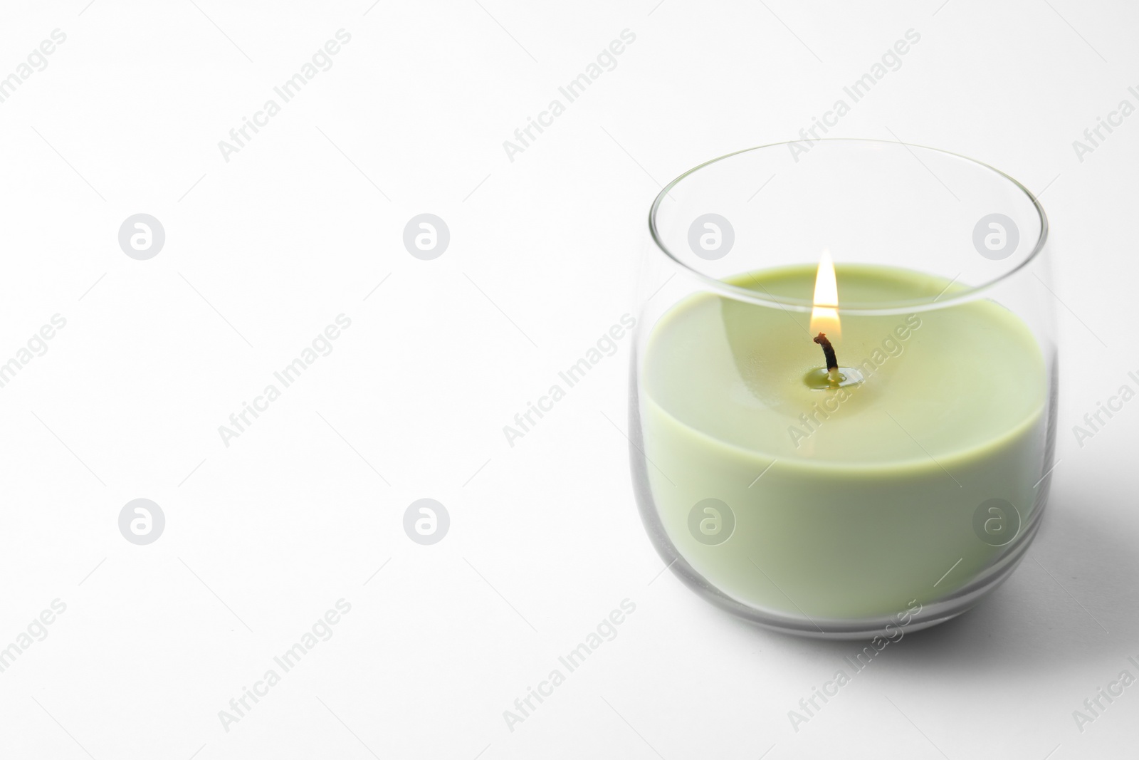 Photo of Green wax candle in glass holder isolated on white