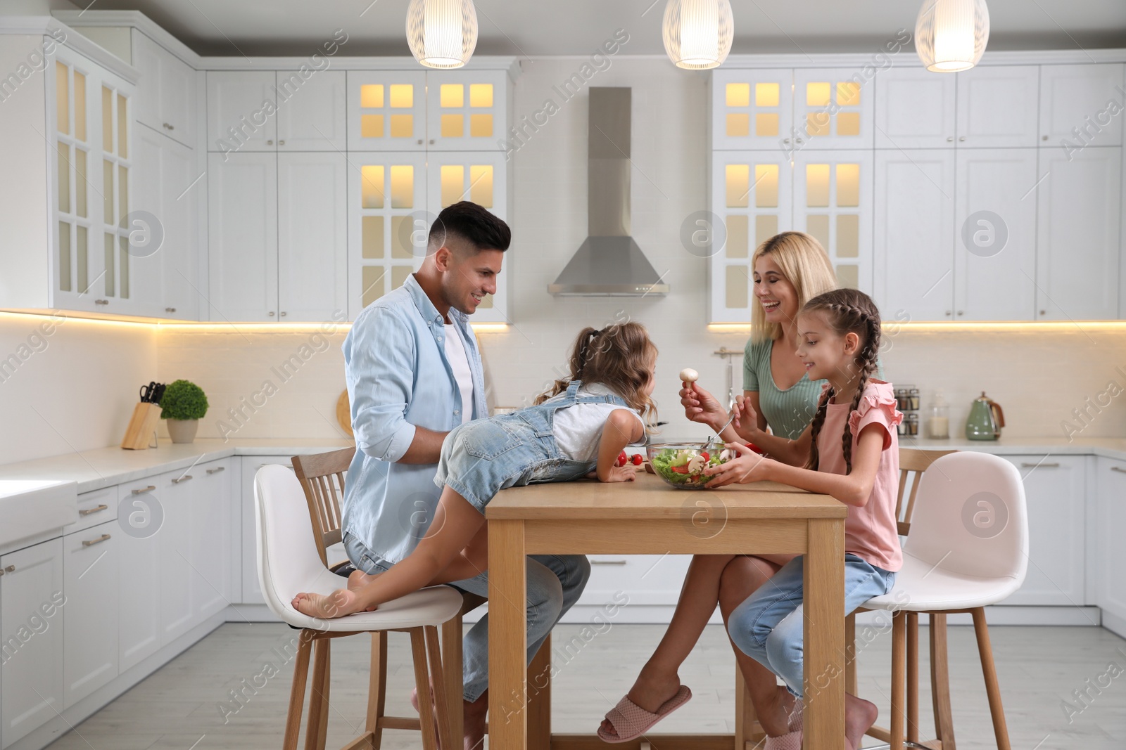 Photo of Happy family cooking together at table in modern kitchen