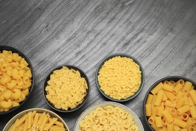 Photo of Different types of pasta on grey table, flat lay. Space for text